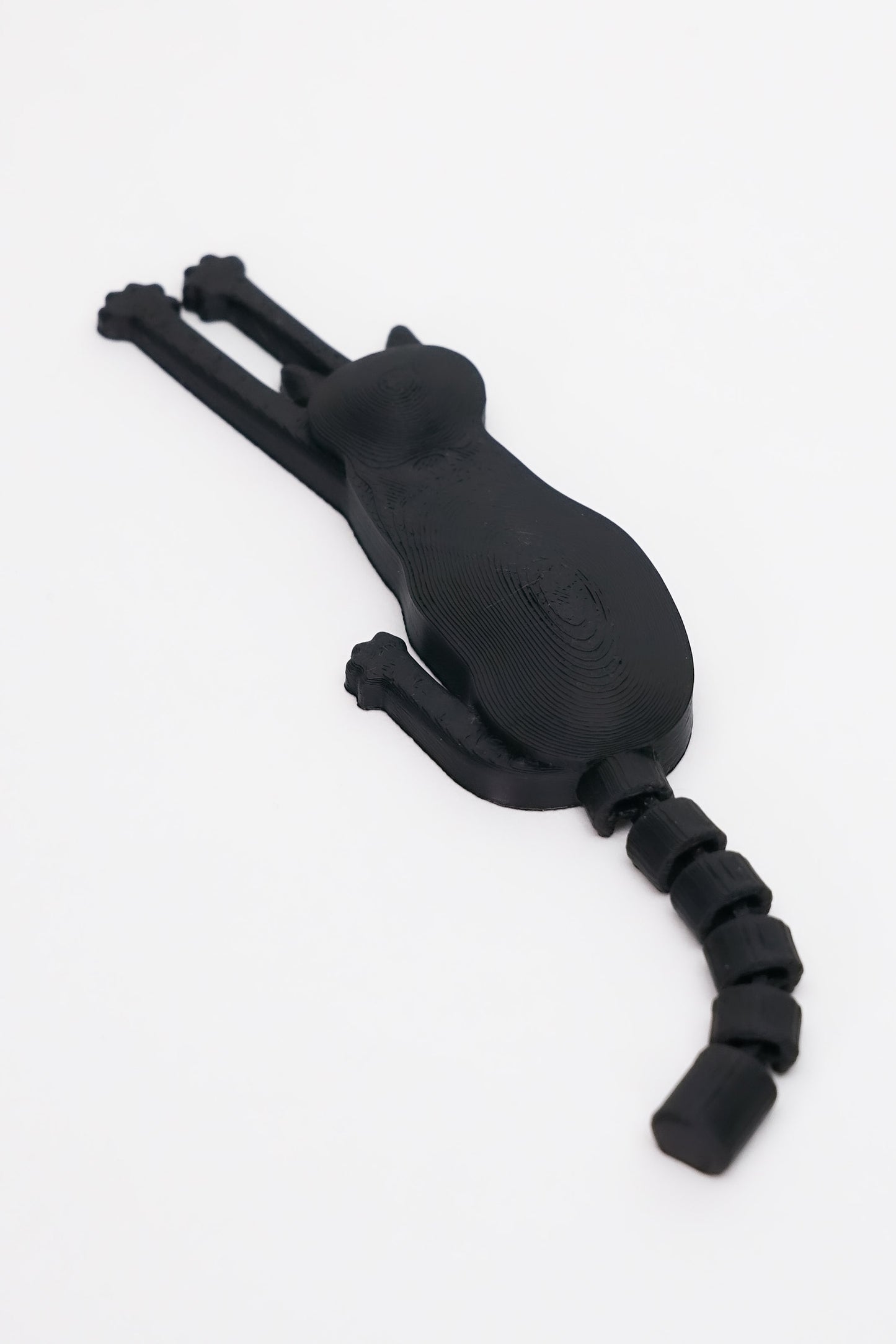 3D printed μαύρης γάτας μαγνητάκι με flexy ουρά σε λευκό φόντο