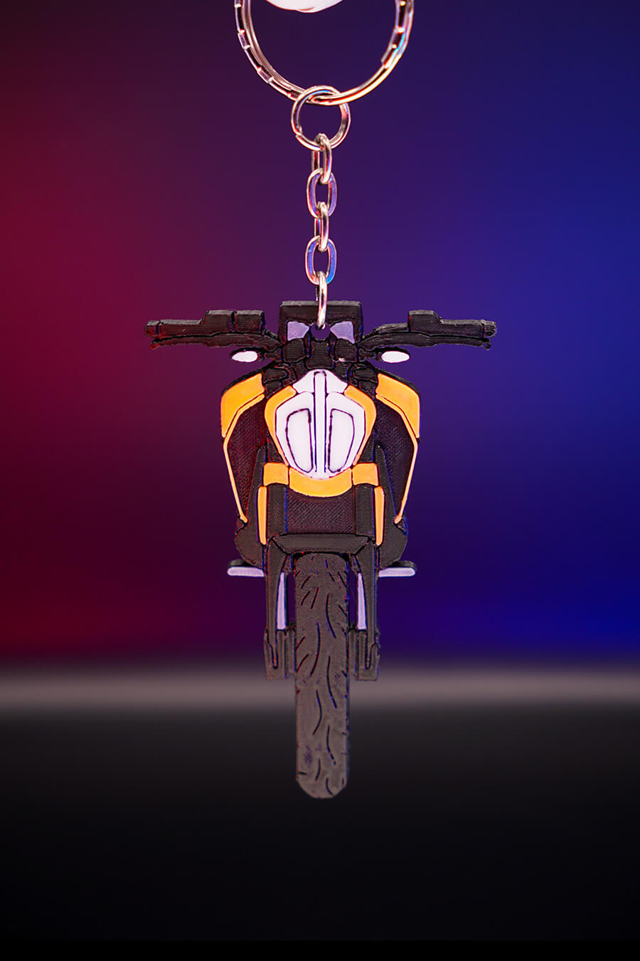 3D printed μπρελόκ KTM Duke 390 σε κάθετη hero λήψη, με φωτισμό φόντου σε μωβ και πορτοκαλί αποχρώσεις, προβολή από μπροστά