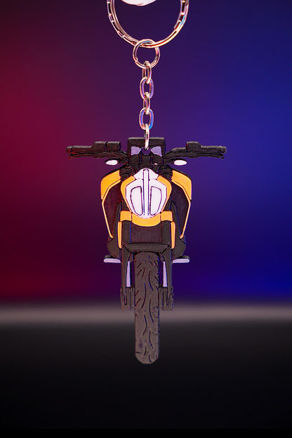 3D printed μπρελόκ KTM Duke 390 σε κάθετη hero λήψη, με φωτισμό φόντου σε μωβ και πορτοκαλί αποχρώσεις, προβολή από μπροστά