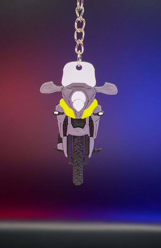 3D printed μπρελόκ Suzuki V-Strom 650 σε κάθετη hero λήψη με φωτισμό φόντου σε μωβ και μπλε αποχρώσεις, προβολή από μπροστά